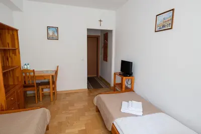 a room with two beds and a table and a television at Pokoje Gościnne Dom św. Szymona in Kraków