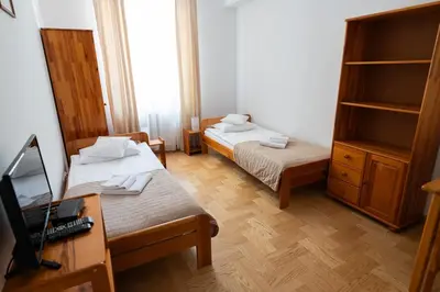 a room with two beds and a desk with a computer at Pokoje Gościnne Dom św. Szymona in Kraków