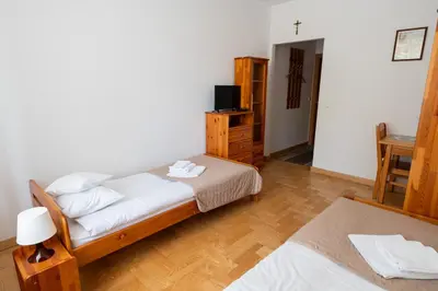 a bedroom with a bed and a dresser and a television at Pokoje Gościnne Dom św. Szymona in Kraków