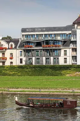 a boat in the water in front of a hotel at Niebieski Art Hotel & Spa in Kraków