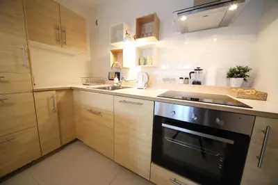 a kitchen with wooden cabinets and a sink and a stove at Kazimierz Friendhouse Apartments in Kraków