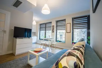 a living room with a couch and a tv and a table at Kazimierz Friendhouse Apartments in Kraków