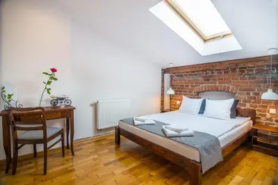 a bedroom with a bed and a desk and a brick wall at Designer Apt in the heart of Kraków 4th floor no lift in Kraków