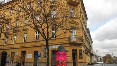 a yellow building with a pink sign in front of it at Designer Apt in the heart of Kraków 4th floor no lift in Kraków