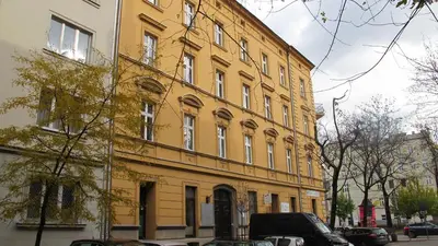a large yellow building with cars parked in front of it at Designer Apt in the heart of Kraków 4th floor no lift in Kraków