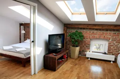 a bedroom with a television and a brick wall at Designer Apt in the heart of Kraków 4th floor no lift in Kraków