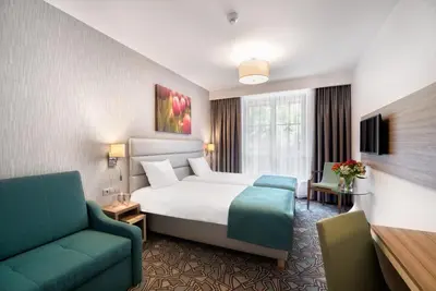 a hotel room with a bed and a couch at Golden Tulip Krakow Kazimierz in Kraków