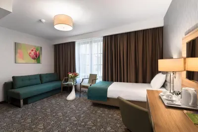 a hotel room with a bed and a couch at Golden Tulip Krakow Kazimierz in Kraków