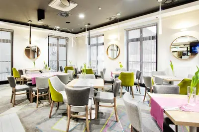 a dining room with tables and chairs and windows at Golden Tulip Krakow Kazimierz in Kraków