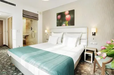 a hotel room with a large bed and a bathroom at Golden Tulip Krakow Kazimierz in Kraków