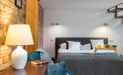 a bedroom with a bed and a table with a lamp at Cracowapart Loft Gertruda in Kraków