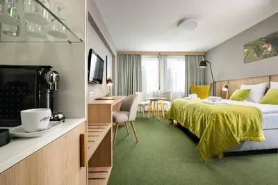 a hotel room with a bed and a table and chairs at Hotel Great Polonia Kraków Airport in Modlniczka