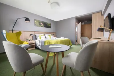 a hotel room with a bed and a table and chairs at Hotel Great Polonia Kraków Airport in Modlniczka
