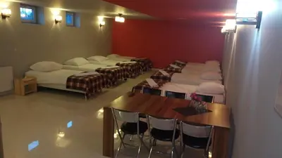 a room with a row of beds and chairs at Hostel Bazar in Kraków