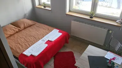 a small room with a bed with a red blanket at Hostel Bazar in Kraków