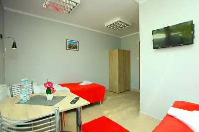 a room with a table and a bed and a television at Hostel Bazar in Kraków