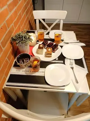 a kitchen with white cabinets and a brick wall at Elpida Apartment in Kraków