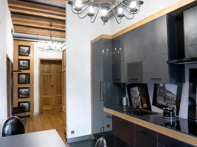 a kitchen with black cabinets and a chandelier at Leonardo 2 in Kraków