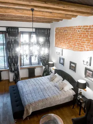 a bedroom with a large bed and a brick wall at Leonardo 2 in Kraków