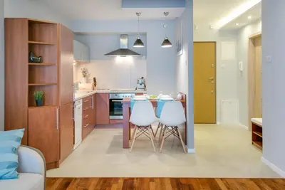 a kitchen with a table and two white chairs at River Boulevards Apartment in Kraków