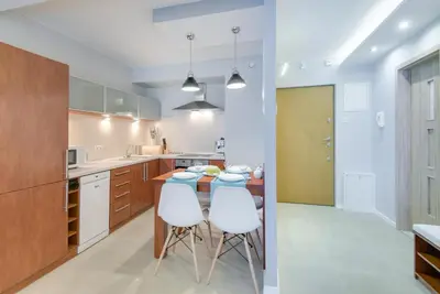 a kitchen with a table and two white chairs at River Boulevards Apartment in Kraków