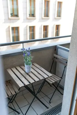 a wooden bench on a balcony with a potted plant at River Boulevards Apartment in Kraków