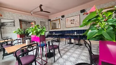 a restaurant with tables and chairs and plants at Pollera in Kraków