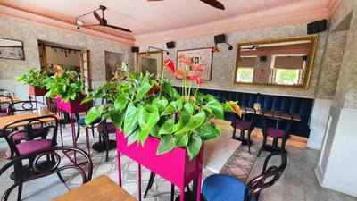 a restaurant with pink tables and chairs and a plant at Pollera in Kraków