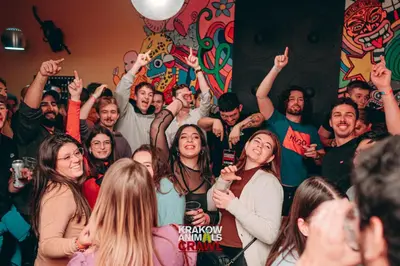 a group of people standing in a room with their hands up at Let's Rock Party Hostel! Age Limit From 18 until 40! in Kraków