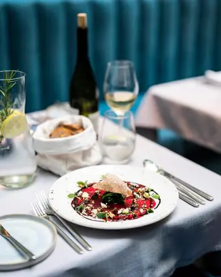 a table with a plate of food and a glass of wine at Hotel Indigo Krakow - Old Town by IHG in Kraków