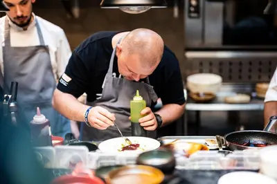 a man preparing a dish in a kitchen at Hotel Indigo Krakow - Old Town by IHG in Kraków