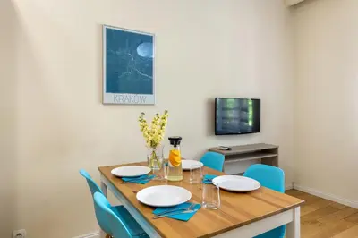a dining room with a wooden table and blue chairs at Królewska Apartments in Kraków