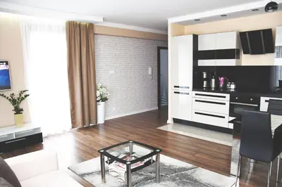 a living room with a table and a kitchen at Apartament Wilga Park in Kraków