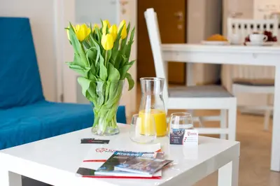 a vase of yellow tulips on a white table at Kraków Apartments - Solna Studio & Apartments in Kraków