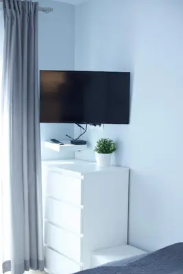 a tv on top of a white dresser with a plant at Kraków Apartments - Solna Studio & Apartments in Kraków