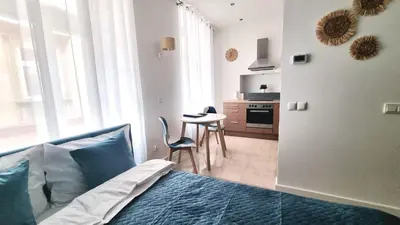 a bedroom with a bed and a kitchen with a table at NOOK NOOK Apartments Katarzyny 2 in Kraków