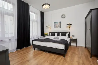 a bedroom with a bed with black curtains and wooden floors at NOOK NOOK Apartments Katarzyny 2 in Kraków