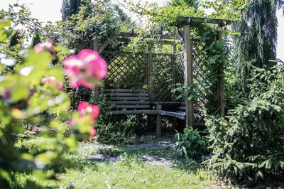 a wooden bench sitting under a pergola in a garden at Apartamenty na Kasztelańskiej in Spytkowice