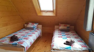 two beds in a log cabin with a window at Beskidzka Chata in Hucisko