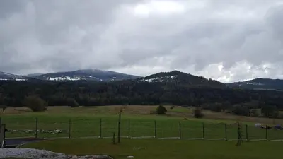a field with a fence and mountains in the background at Beskidzka Chata in Hucisko