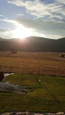 a view of a field with the sun in the distance at Beskidzka Chata in Hucisko