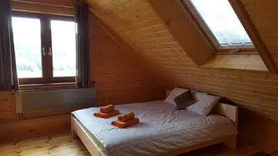 a bed in a wooden room with two teddy bears on it at Beskidzka Chata in Hucisko