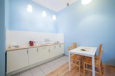 a kitchen with white cabinets and a table and chairs at Dizzy Daisy Downtown Apartments in Kraków