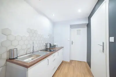 a white bathroom with a sink and a door at Dizzy Daisy Downtown Apartments in Kraków