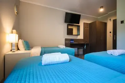 a hotel room with two blue beds and a desk at B&M Guesthouse in Oświęcim