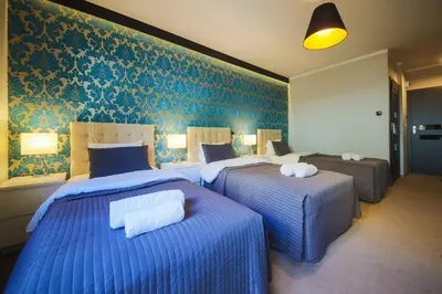 two beds in a hotel room with blue wallpaper at B&M Guesthouse in Oświęcim