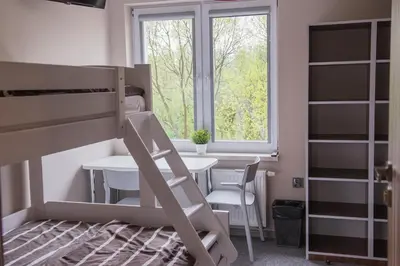 a bedroom with a bunk bed with a table and a window at B&M Guesthouse in Oświęcim
