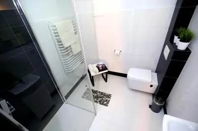 a white bathroom with a shower and a toilet at Pure Apartments Kraków in Kraków