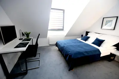 a bedroom with a bed and a desk with a computer at Pure Apartments Kraków in Kraków
