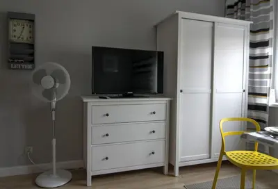 a bedroom with a white dresser with a television and a fan at Apartment I GrayFor2 Old Town Kraków in Kraków